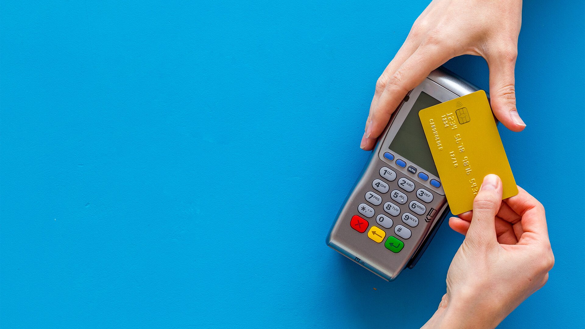Closeup of hands using contactless payment and credit card against a blue background