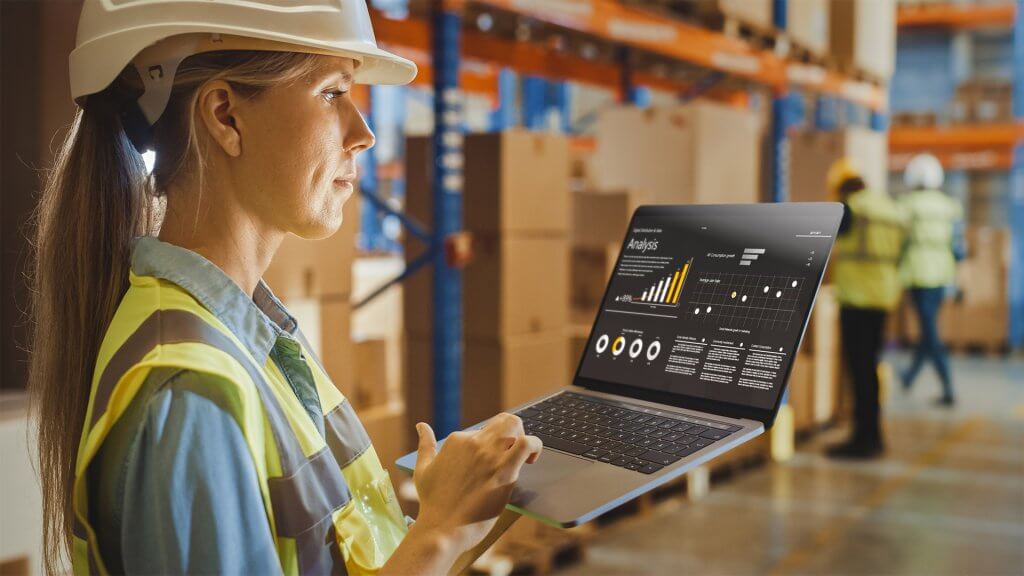 Logistics worker in a warehouse, using a laptop with software to help the buisness
