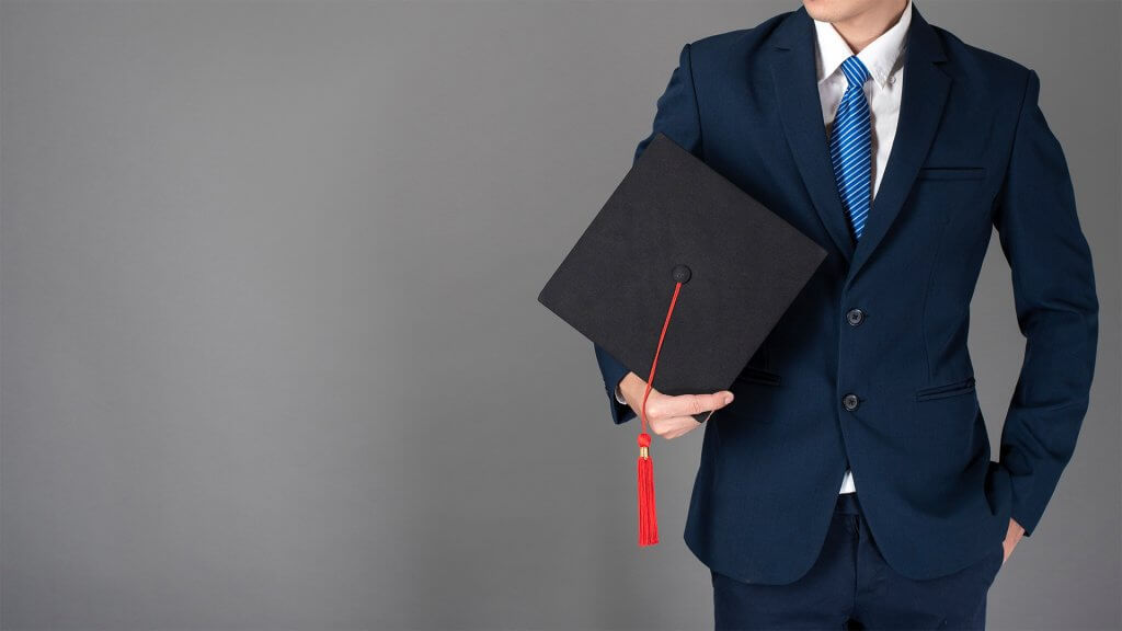 Man in a business suit holding a graduation cap