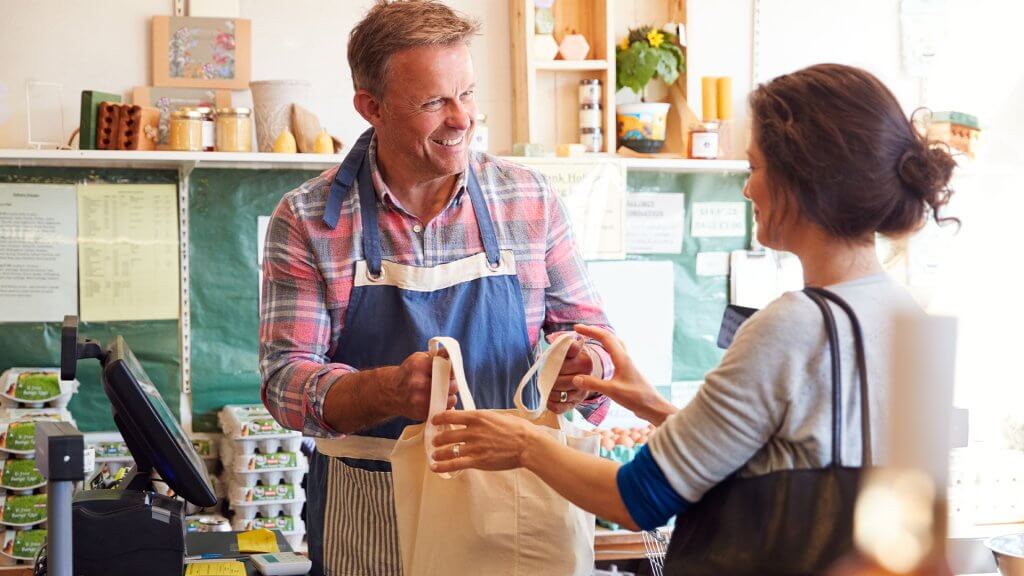 Sales Assistant Serving Female Customer At Checkout Of Organic Farm Shop