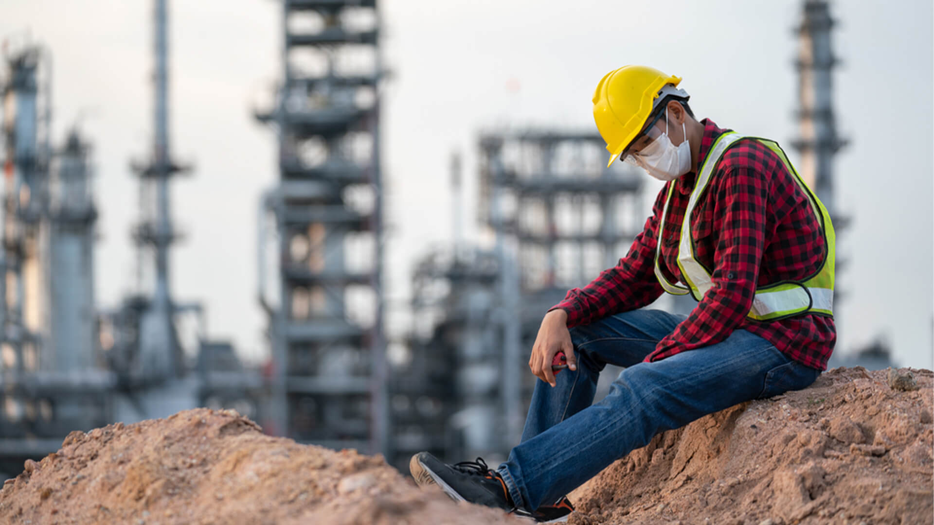 stressed oil and gas worker sitting outside on a rock