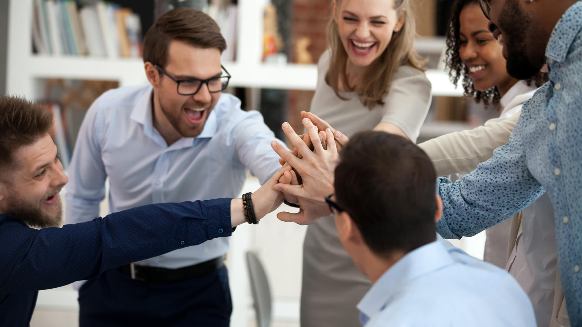 Excited motivated multi-ethnic team people give high five in office