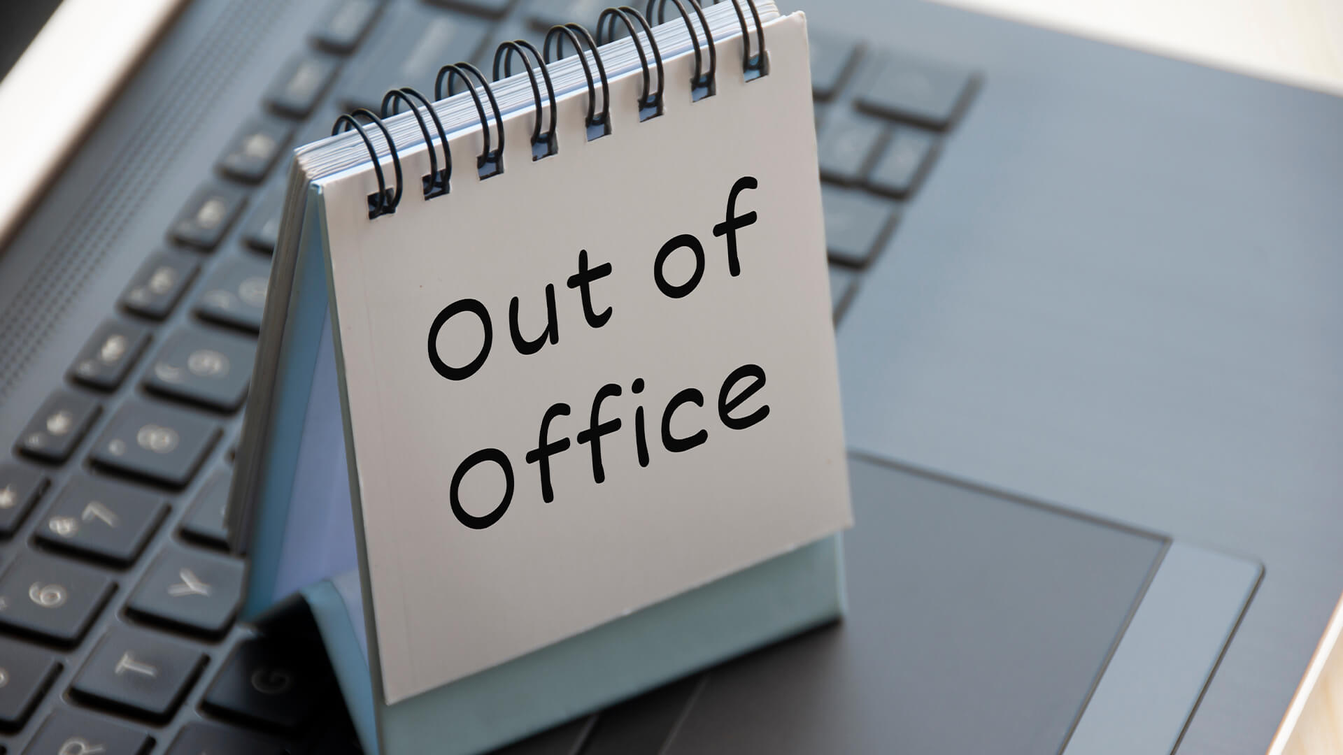 Out of office text on calendar desk on top of a laptop.